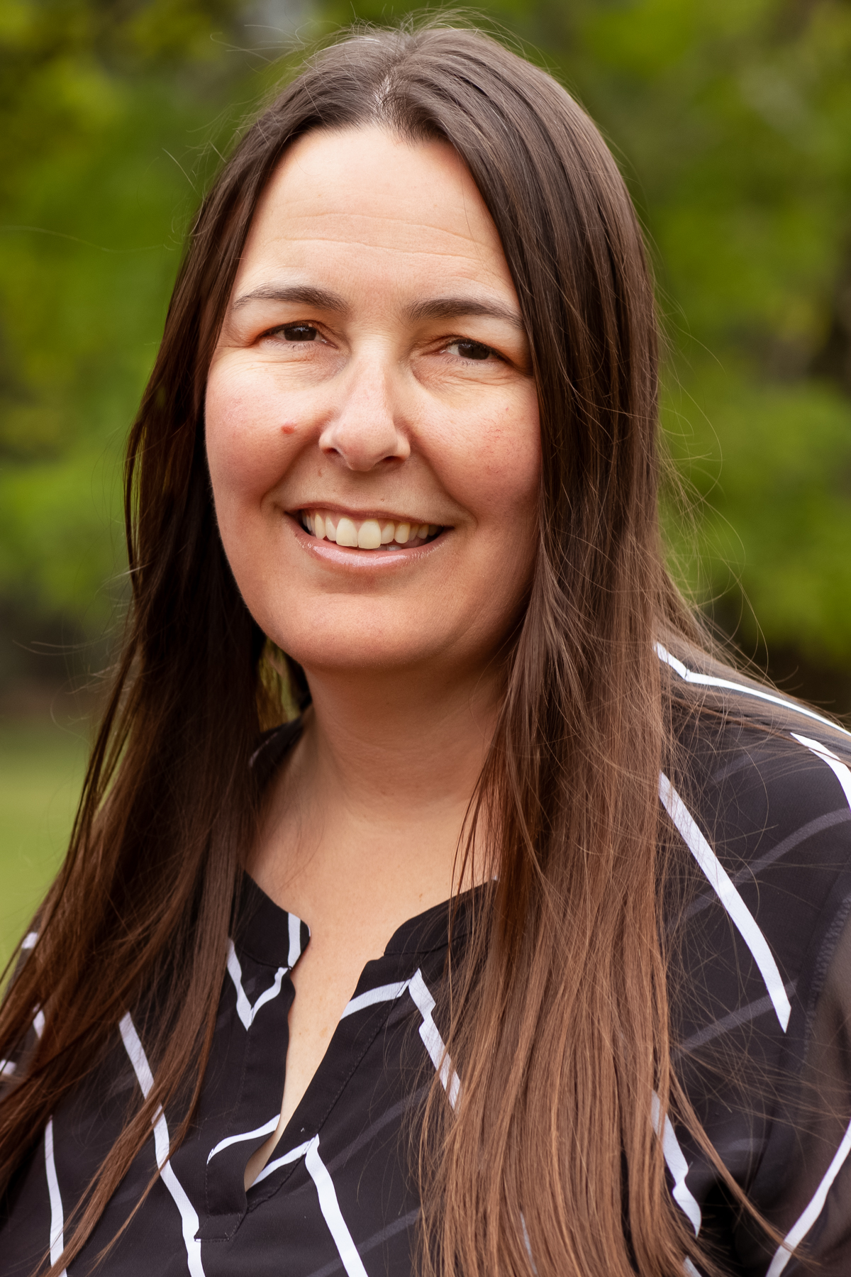 Tania Innes, IBCLC and Speech Pathologist, smiling warmly outdoors in soft natural light.